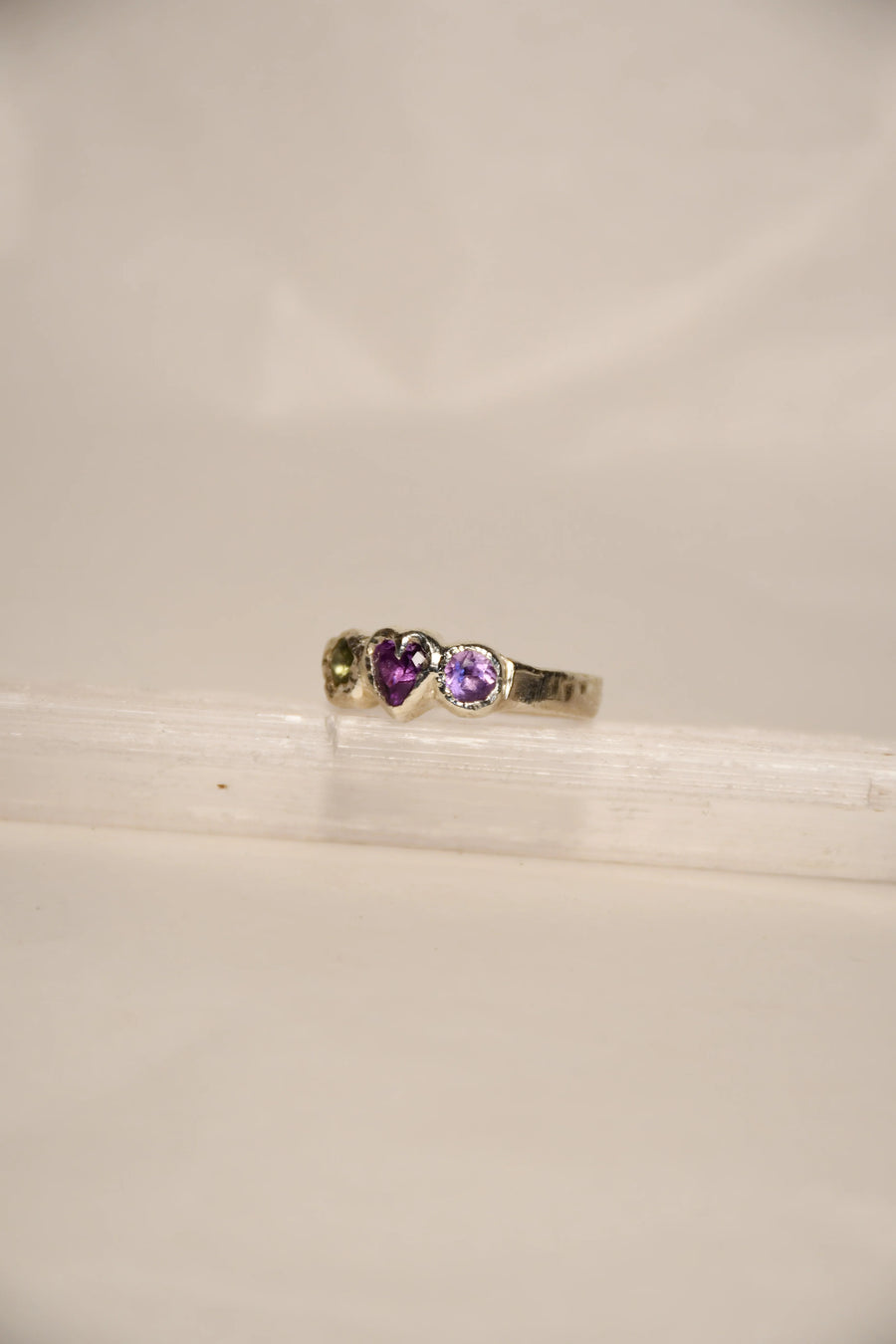 Silver ring with purple gemstones on a white background
