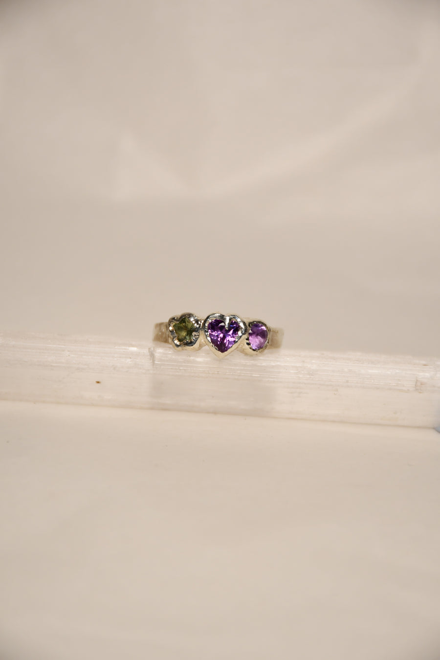 Close-up of a silver ring with three colored stones on a white background