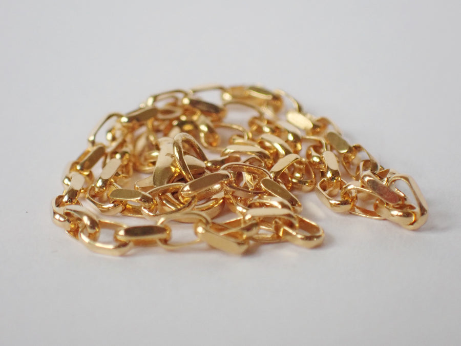 Oval Belcher Chain Bracelet, Yellow gold, curled up in a pile, on a white background
